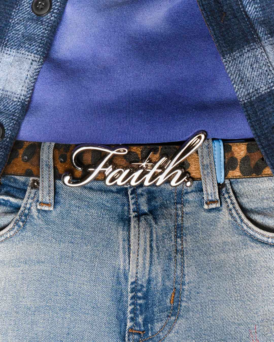 Model wearing a leopard faux belt with a chrome 'Faith' buckle, paired with blue denim jeans and a blue shirt